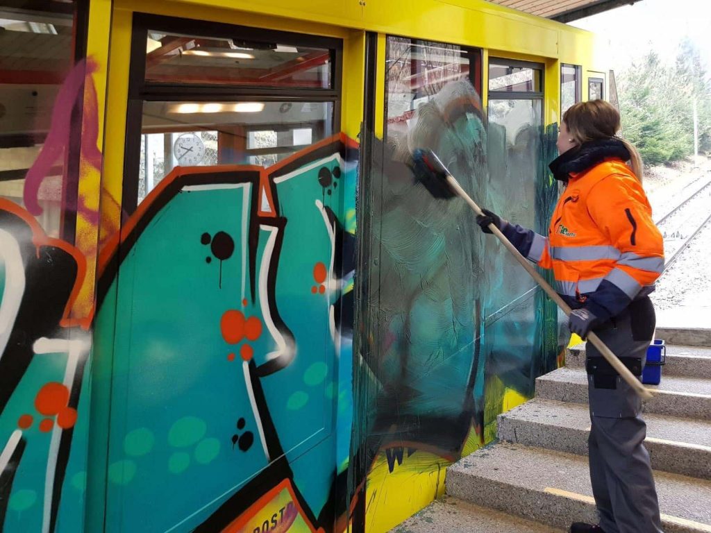 worker removing graffiti from a train in Switzerland